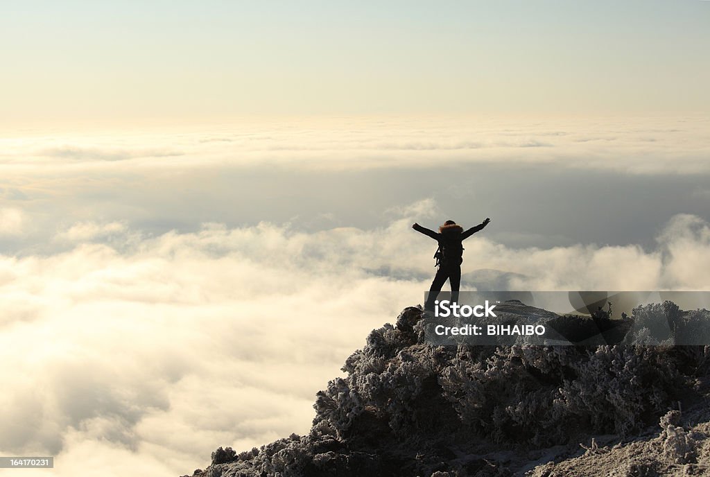 on top of the mountain Woman standing on top of the mountain with his hands raised Reaching Stock Photo