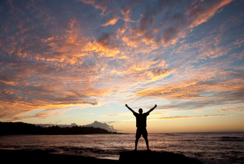 A silhouette of a man raising his arms in worship by the sea. Themes include praise and worship, men, alone, meditation, spirituality, singing, prayer, celebration, accomplishment, success, travel, tourism, and happiness. One middle-aged man, unrecognizable, is in the image. Image taken with Canon 5d Mark II and L series lens. 