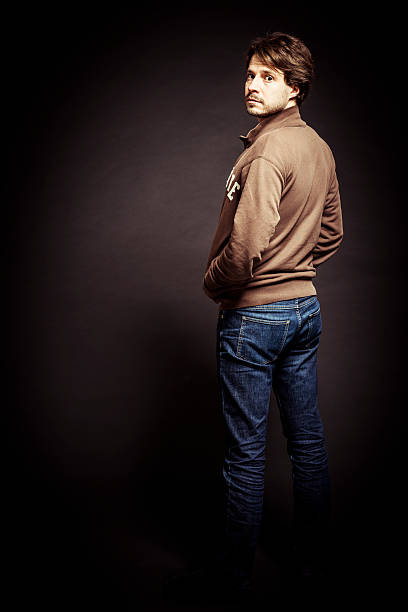 retrato de hombre con pared marrón en el estudio, vista posterior - turn back fotografías e imágenes de stock