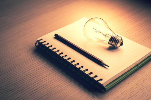 istock Blank notebook and pencil with light bulb on wooden table.creative ideas of writer, thinking for work on desk 1641734700