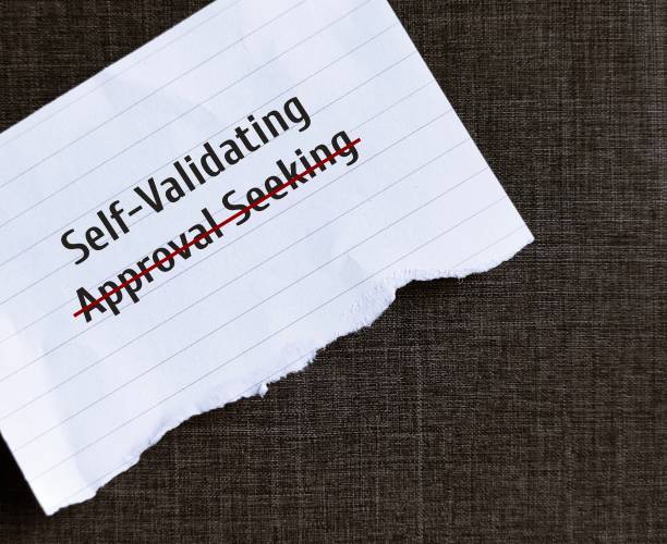 istock Torn paper on black background with text written APPROVAL SEEKING crossed off to SELF-VALIDATING, to overcome addiction to approval and validation from others and have self-validating instead 1641736869