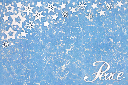 Peace on earth at Christmas abstract background on mottled blue with star and snowflake decorations. Festive happy holidays, New Year, Noel, winter theme.