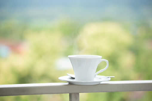 A white cup of coffee with natural background in the garden, aroma coffee beverage