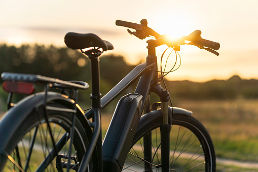 Front view of a black electric bike parked in a pristine natural landscape in the evening sun
