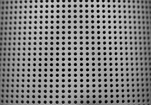 Silver speaker lattice close-up. Perforated metal texture. Modern industrial metal mesh music speaker grille