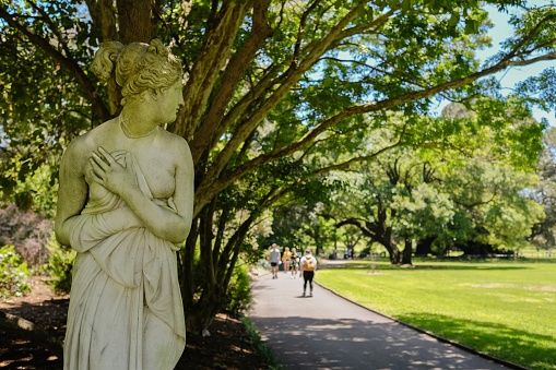 Pedestrians walk past a marble replica of the Venus Italica statue by Antonio Canova on a sunny spring  morning at the Royal Botanic Gardens in Sydney — New South Wales, Australia