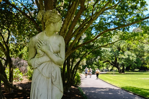 Pedestrians pass by a marble replica of the Venus Italica statue on a sunny spring  morning at the Royal Botanic Gardens in Sydney — New South Wales, Australia