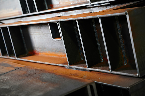 Metal fabricated assemblies stored in plant warehouse close view. Metal details for construction site. Steel supplies in plant workshop