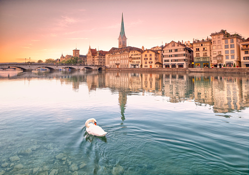 a warm sunrise in the historic center of Zurich on the banks of its river.