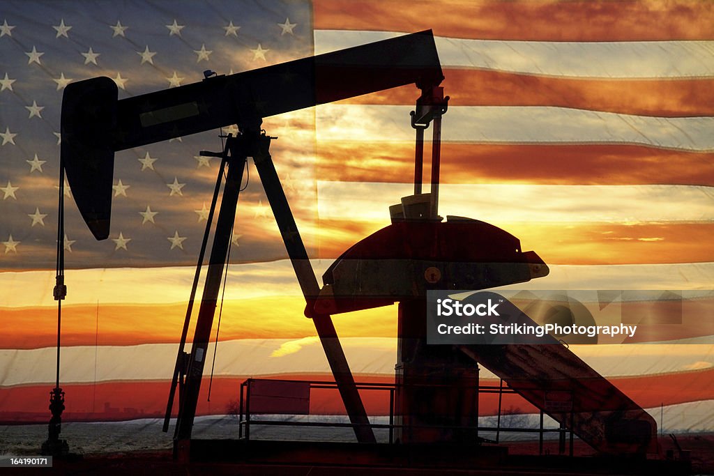 American Oil Landscape image of a oil well pumpjack wiith an early morning golden sunrise and American USA red White and Blue Flag background. Patriotism Stock Photo