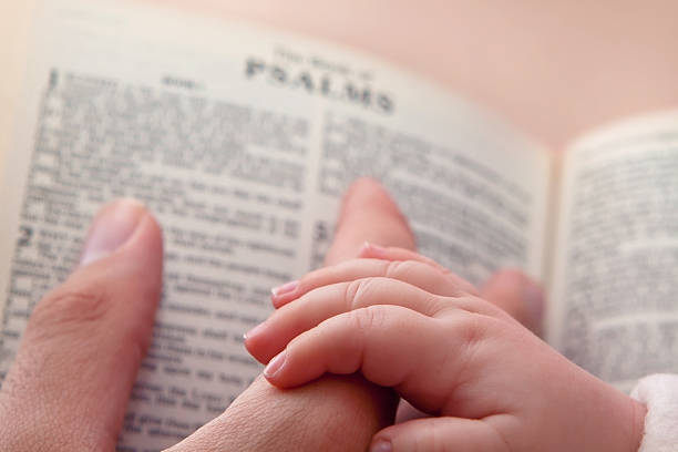 istock Baby Holding Dad's Finger on Bible 164190457