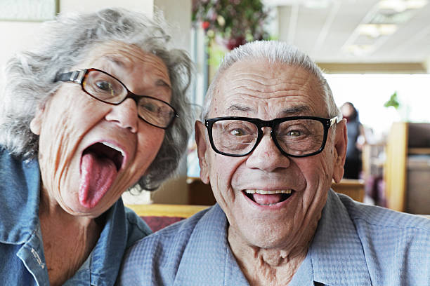 Grandpa and Grandma Making Faces A senior couple having fun making silly faces. This time, it's Grandma photo bombing Grandpa's "portrait". :) photo bomb stock pictures, royalty-free photos & images