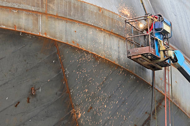 Man welding seams on hull of ship under construction