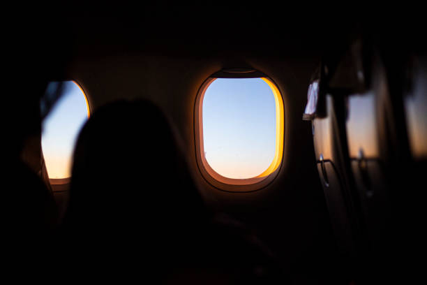 istock Airplane tiny window shape lighting a dark interior in an airplane flying 1641934027