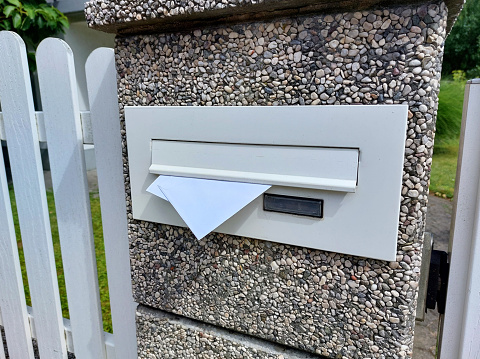 School boy opening a post box and checking mail. Kid waiting for a letter, checking correspondence and looking into the in the metal mailbox.