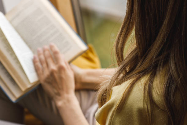 istock Woman relaxing on the window sill and reading a book 1641956857