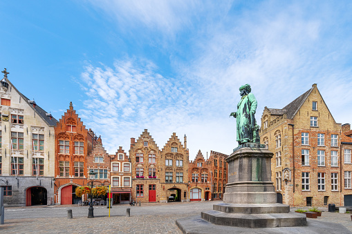 Jan Van Eyck Square and Monument in Bruges. Flemish architecture buildings in the background .
