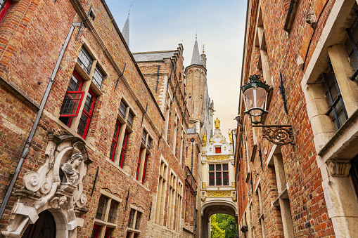 Historical brick houses, statues and old fashion corridor in narrow streets of Bruges, Belgium