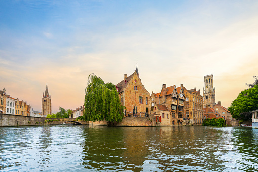 Rosary Quay in Bruges. General view of the old historic and touristic city of Belgium, Bruges medieval bell tower and historic houses from the water canal in summer.