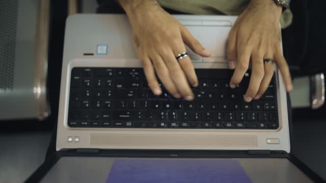 Top view of hands typing on keyboard of laptop
