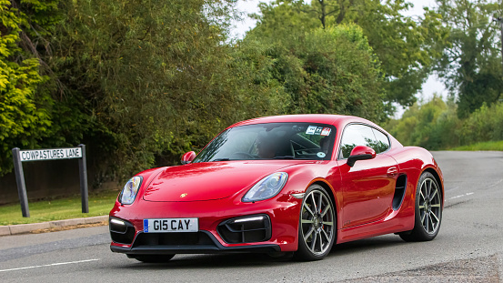 Whittlebury,Northants,UK -Aug 26th 2023:  2016 red Porsche Cayman GTS car travelling on an English country road