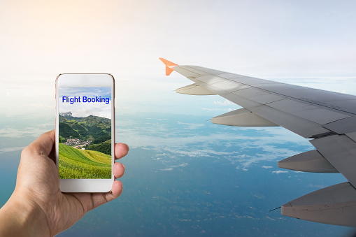 Mobile phone with airplane wing in the background, Booking flight on mobile application concept