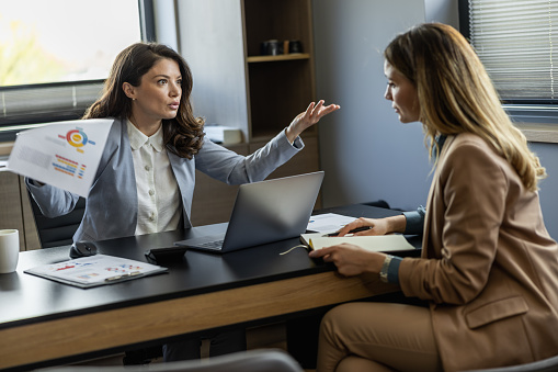 Angry boss yelling at her employee, she is stressed and feeling frustrated on work.Young ambitious female boss yelling at new unhappy female employee.Mobbing at work.