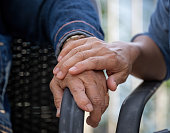 Hand of a senior woman is comforted by the hand of her daughter. Care and holding hands together.