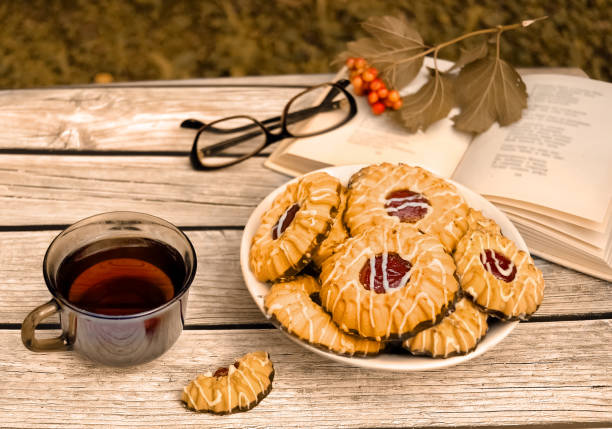 Tea with qurabiya sand cookies while reading book in fall garden. Autumn dessert.