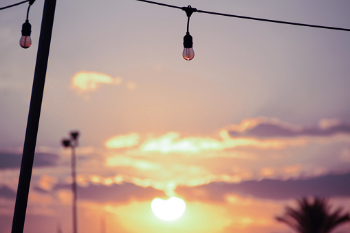 image of a defocused sunset prioritizing an unlit light bulb hanging in the top center of the scene