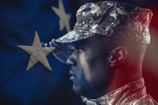 An American soldier at attention. Composite with the American flag.