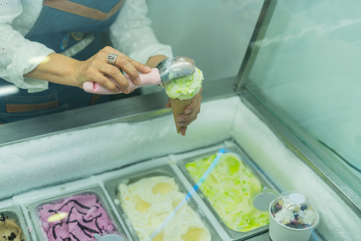 average age 40-year-old Latina woman dressed formally entrepreneurial owner of a small ice cream business serves her customers by serving them a delicious ice cream