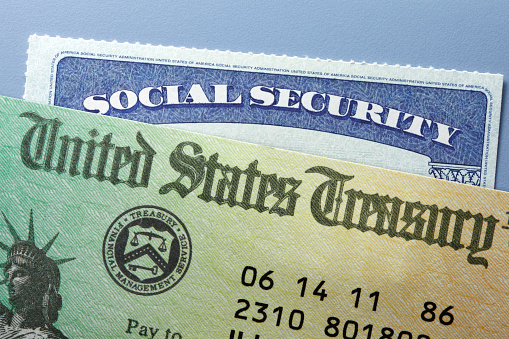 A United States Treasury government check rests on top of a Social Security card.