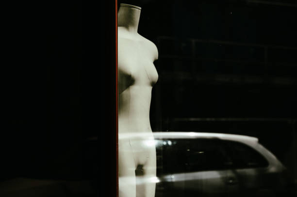 Abstract view of a mannequin with a mirrored passing car with a black background