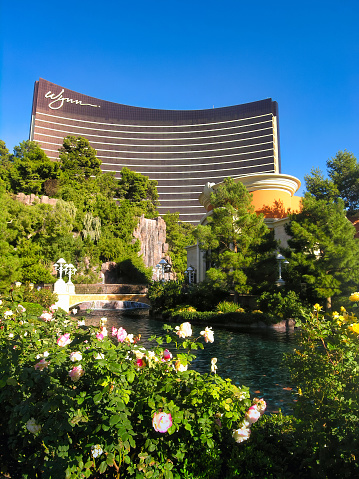 Wynn hotel surrounded by trees and flowers in Las Vegas, Nevada. The hotel is a luxury hotel, and it is located on the Las Vegas Strip.