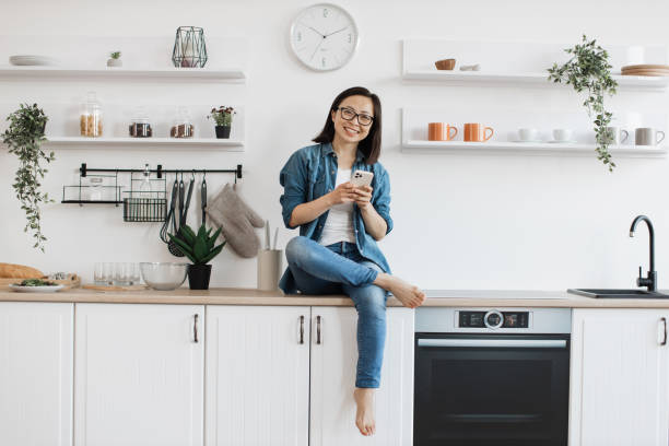 istock Joyful female typing on phne while relaxing in kitchen 1642272717