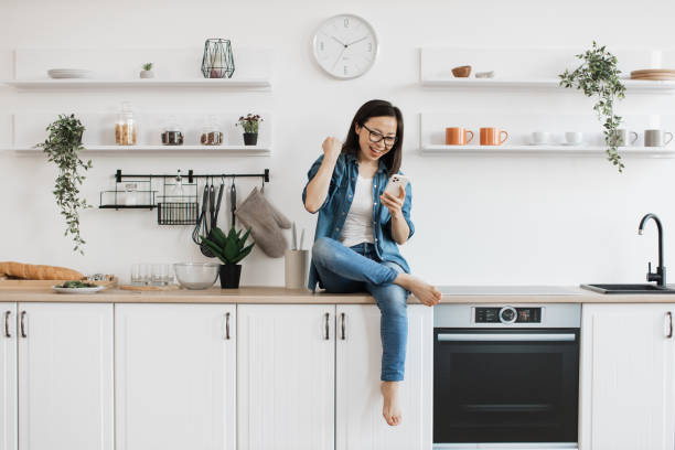 istock Woman checking email via smartphone on countertop in kitchen 1642272721