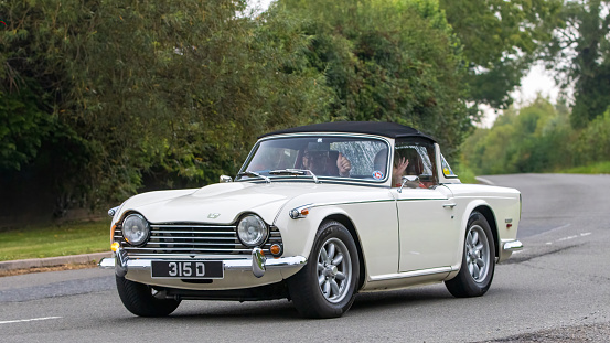 Whittlebury,Northants,UK -Aug 26th 2023: 1968 white Triumph TR5 car travelling on an English country road