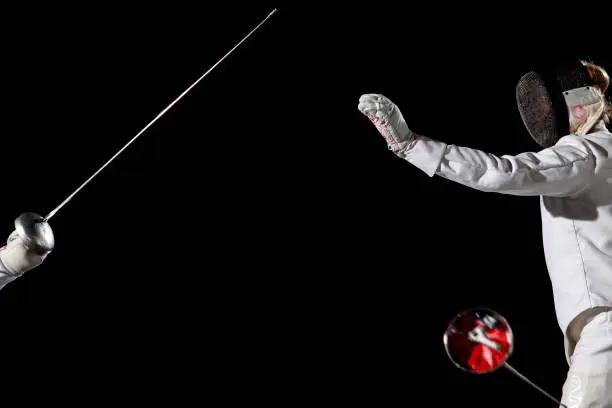 Two fencer batteling. One is attacking and the other one lost his sword. White on black background.