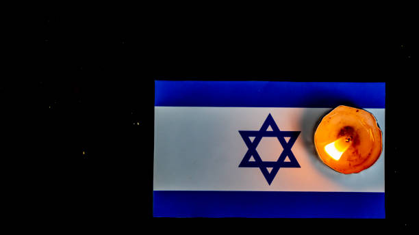 istock Israeli flag and candles burning above it, Holocaust memory day 1642354042