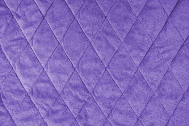 istock Quilted purple velours fabric background, wrinkled soft blanket surface 1642366634