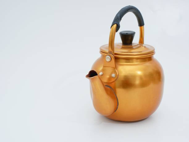 Gilded metal kettle on an isolated white background.Golden teapot
