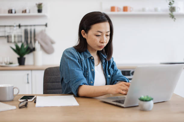 istock Female adult using portable device in kitchen interior 1642378677
