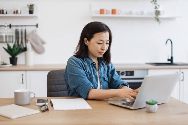 istock Female adult using portable device in kitchen interior 1642378681