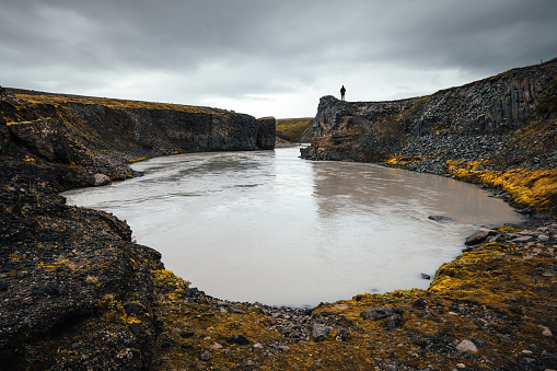 Woman looking down on a glacial river in the Central Highlands of Iceland.