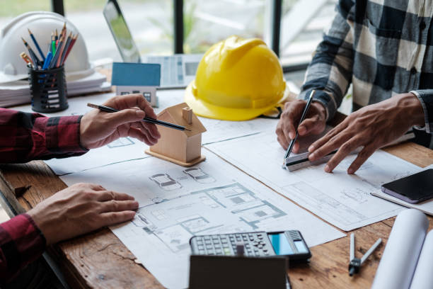 istock A group of engineers working through blueprints and model houses on their desks. 1642380854