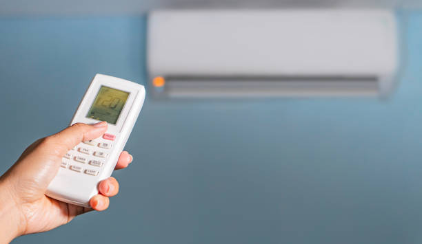 istock Air conditioner temperature adjustment with remote controller in room at home. 1642402644