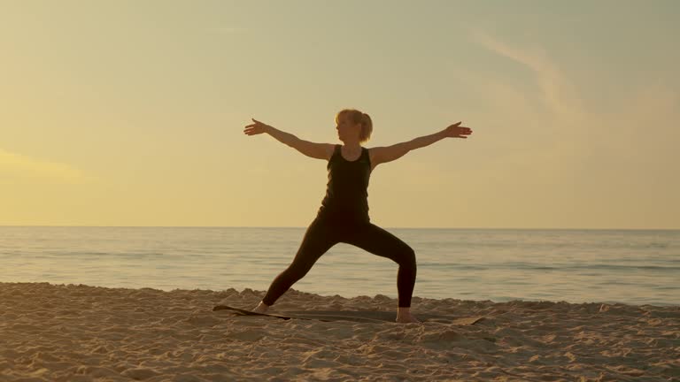 Middle years woman practice medicine yoga in meditation pose on sea beach lotus position asana balance kundalini energy every day routine exercising