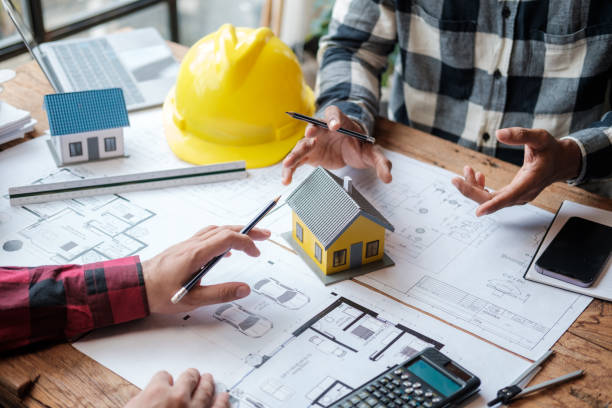 istock A group of engineers working through blueprints and model houses on their desks. 1642428032