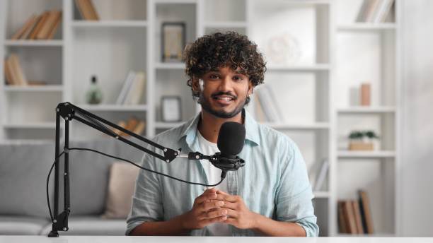 istock Microphone, podcast and Indian man speaker in his living room. Creative streamer, internet influencer or online content creator live streaming for audience. Camera view. 1642429383